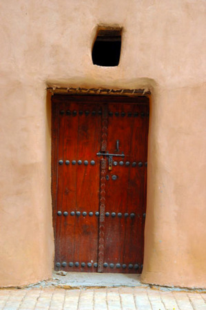 باب خشبي تراثي وجدار مبني من الجص يمثل القصر الاحمر في الكويت وهو من الاماكن التاريخية في الكويت