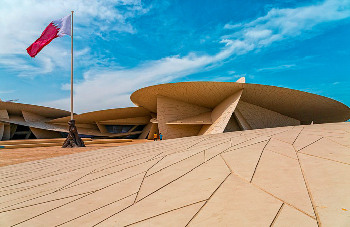 تصميم بناء حديث وبجانبه علم قطر ، متحف قطر الوطني
