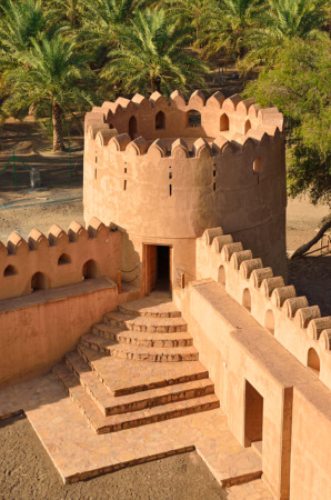 حصن مقرنص ، بناء معماري شاهق يحتوي على سلم ويحيط به النخيل يقع في ولاية بهلاء