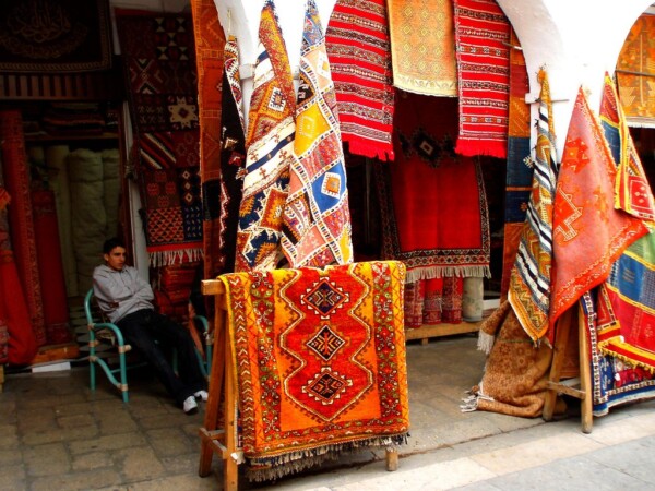 بائع السجاد المغربي يجلس بجوار السجاد الذي يبيعه 