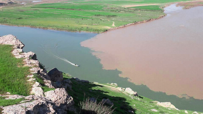 قارب ونهر و مساحات خضراء تمثل قرية السفينة في الموصل